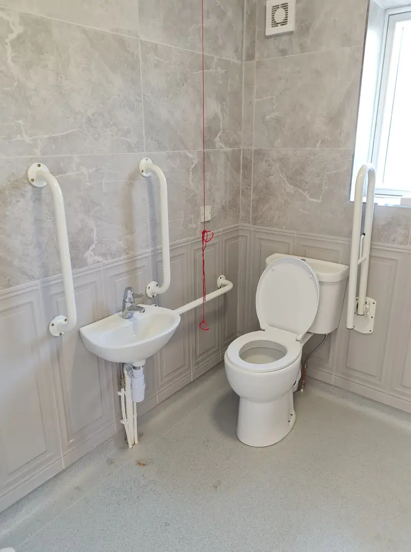 Accessible bathroom fit-out with grab rails and tiled walls